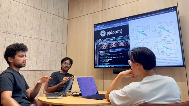 Die drei Informatik-Studierenden Mihir Mahajan, Franz Srambical und Alfred Nguyen sitzen vor einem Monitor.