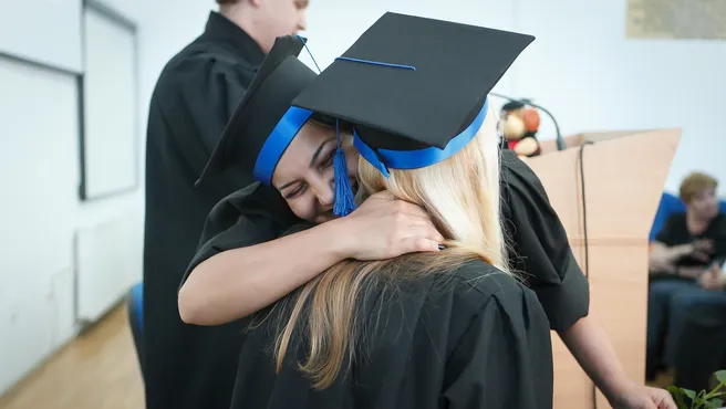 Two women with doctor's hats embrace